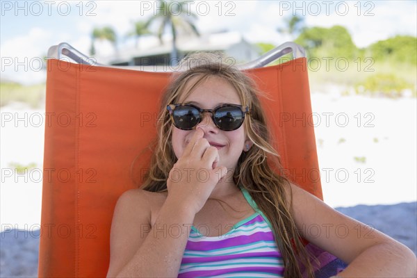 Caucasian girl picking nose on beach