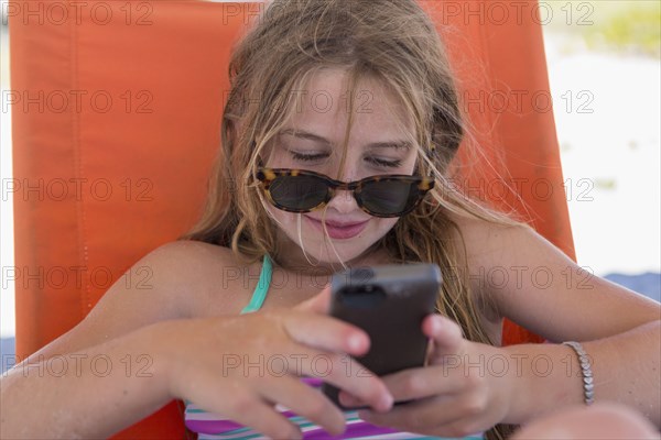 Caucasian girl using cell phone on beach