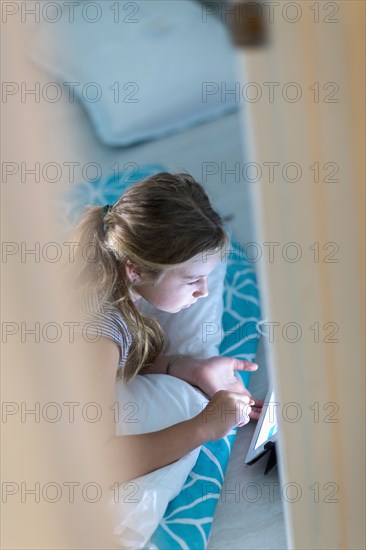 Caucasian girl using digital tablet on bed at night