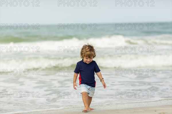 Caucasian baby boy walking on beach