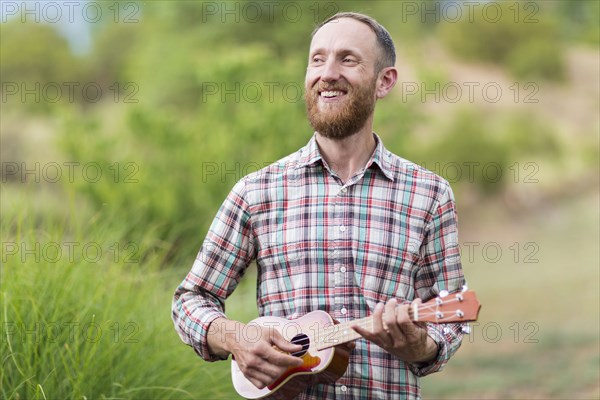 Caucasian man playing ukulele outdoors