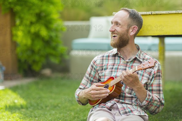 Caucasian man playing ukulele in backyard