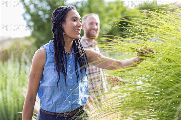 Woman examining tall plants in garden