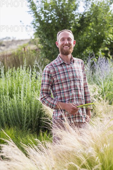 Caucasian man admiring tall plants in garden