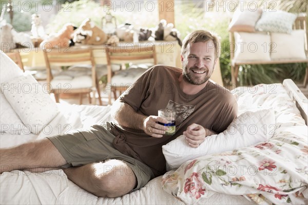 Caucasian man drinking on bed