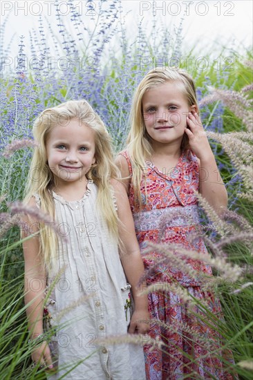 Caucasian sisters standing in tall grass