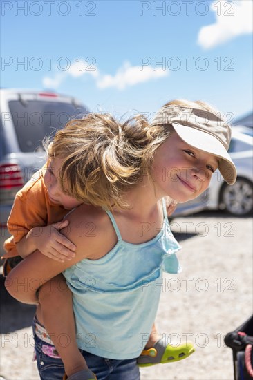 Caucasian girl carrying brother piggyback