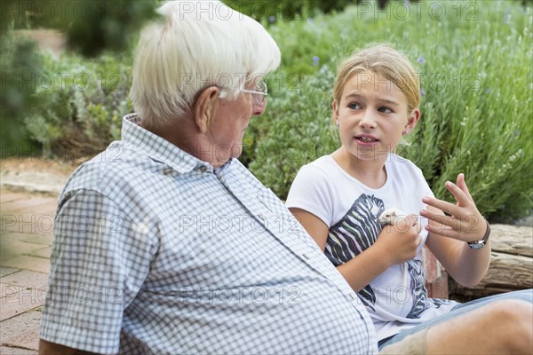 Caucasian grandfather and granddaughter talking in garden