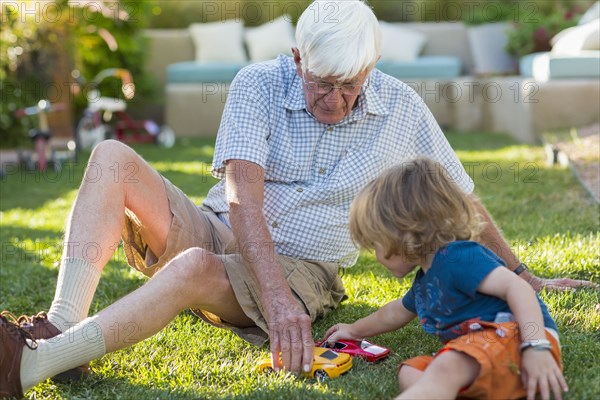 Caucasian grandfather and grandson playing on lawn