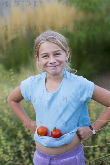 Caucasian girl carrying tomatoes in shirt