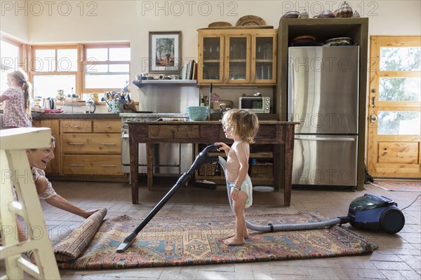 Caucasian brother and sister vacuuming rug