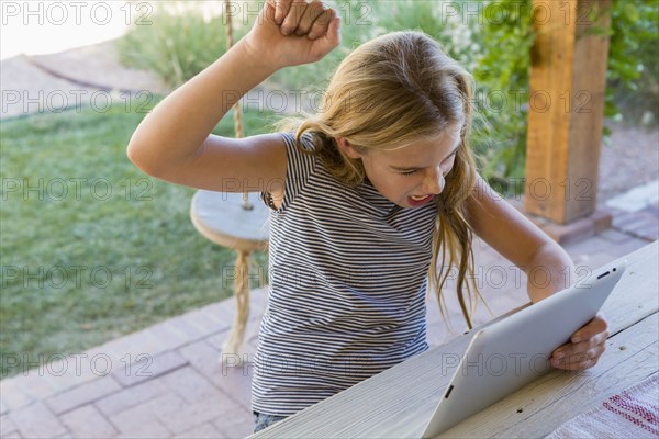 Caucasian girl cheering at digital tablet