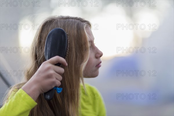 Caucasian girl brushing her hair outdoors