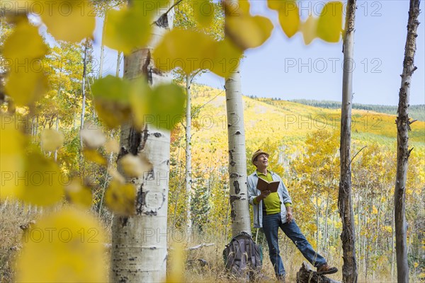 Man reading book in autumn forest