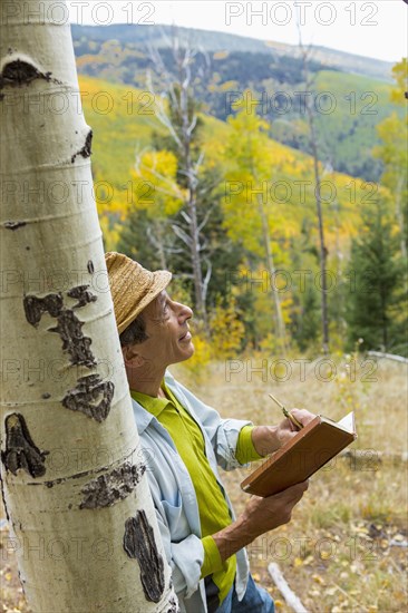 Man reading book in autumn forest