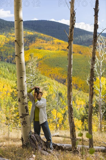 Man photographing with camera in autumn forest