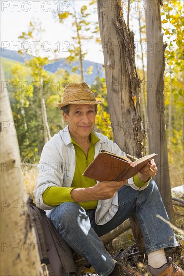 Man reading book in autumn forest