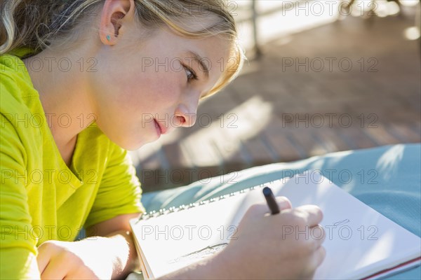 Caucasian girl drawing outdoors