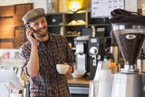 Caucasian man talking on cell phone in cafe