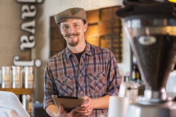 Caucasian barista holding digital tablet in cafe