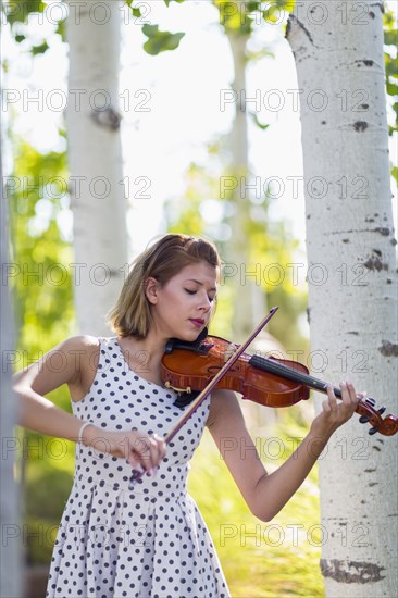 Mixed race musician playing violin outdoors