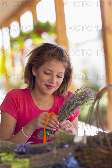 Mixed race girl tying bundle of flowers