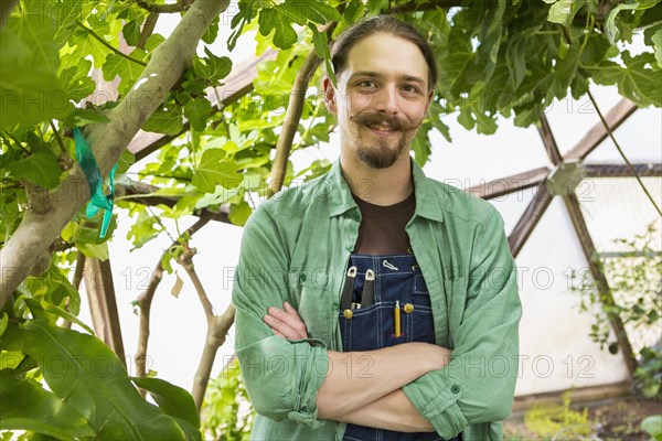 Caucasian gardener smiling in greenhouse