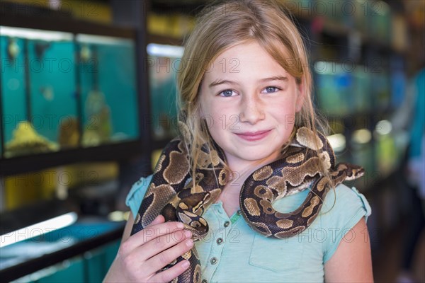 Caucasian girl holding snake in pet store