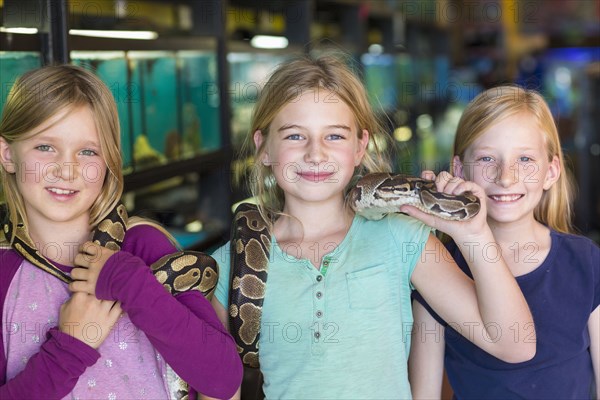 Caucasian girls playing with snake in pet store