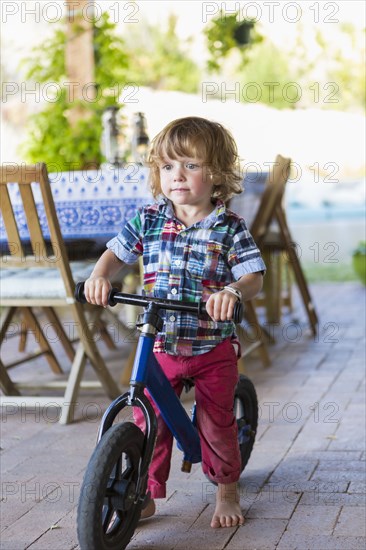 Caucasian boy riding bicycle on patio