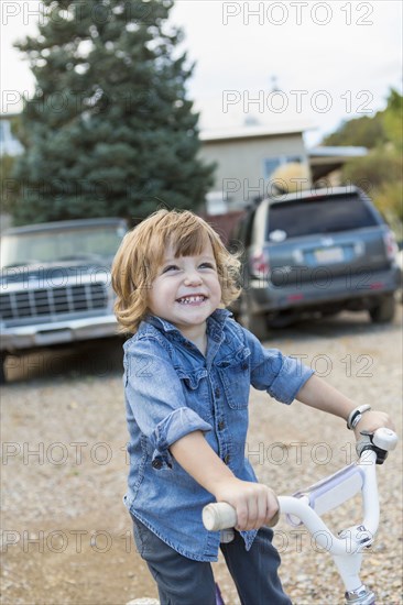 Caucasian boy riding tricycle in gravel