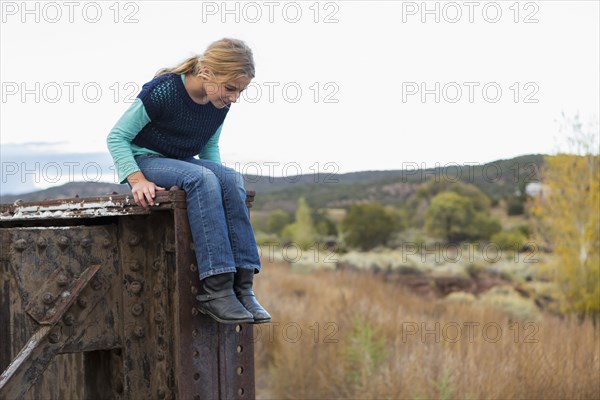 Caucasian girl sitting on structure outdoors