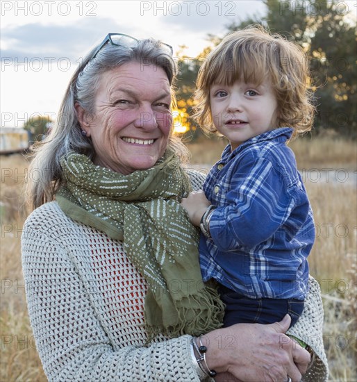 Caucasian grandmother holding grandson outdoors