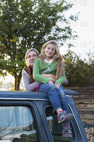 Caucasian mother and daughter hugging on truck roof