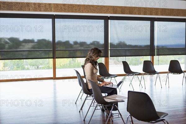 Hispanic businesswoman using laptop in meeting room