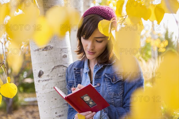 Hispanic woman writing in tree