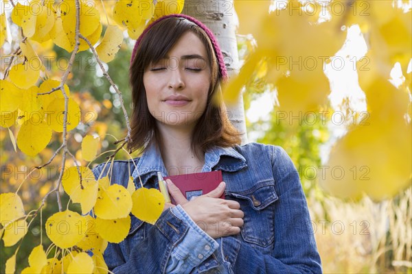 Hispanic woman holding diary in tree