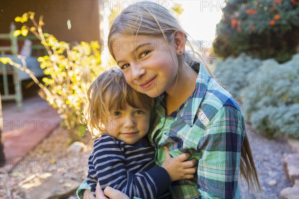 Caucasian brother and sister hugging outdoors