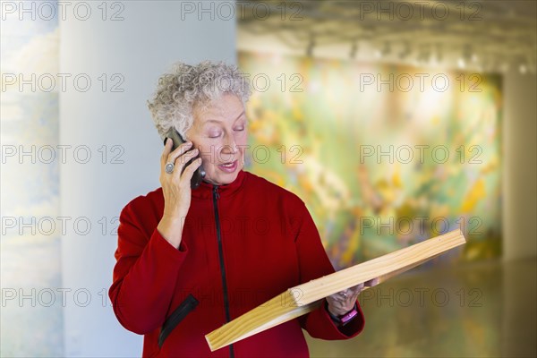 Older mixed race woman talking on phone in art gallery