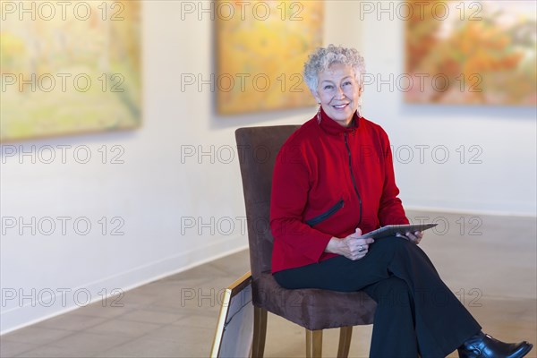 Older mixed race woman using digital tablet in art gallery