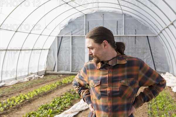 Caucasian farmer standing in greenhouse