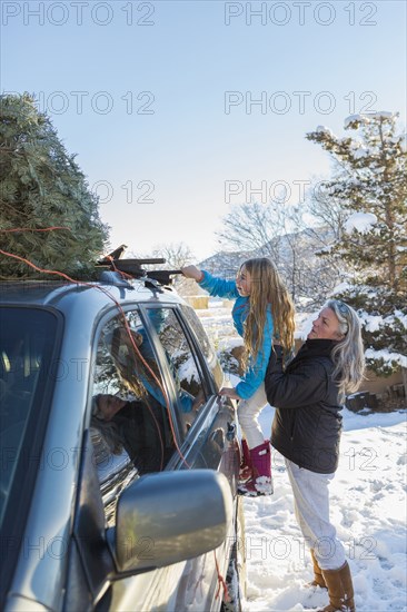 Caucasian mother and daughter hauling Christmas tree