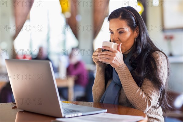 Hispanic woman using laptop in cafe