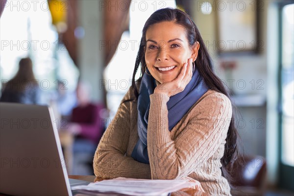 Hispanic woman using laptop in cafe