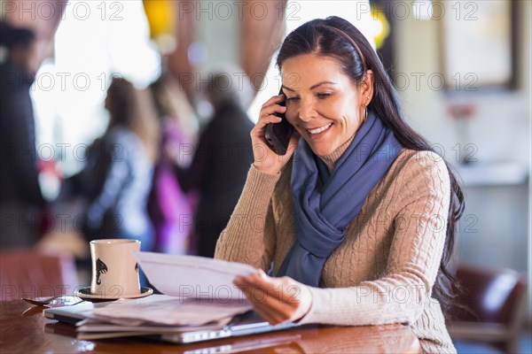Hispanic woman talking on cell phone in cafe