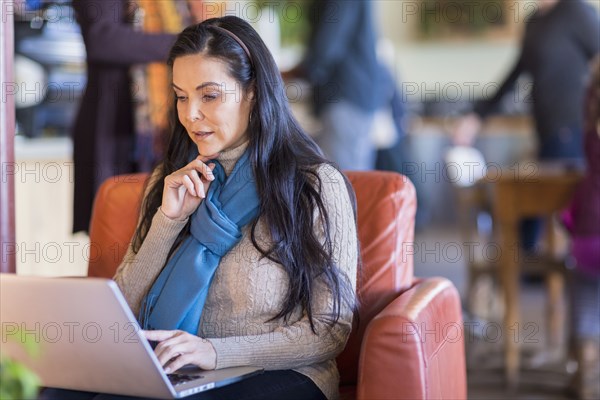 Hispanic woman using laptop in cafe