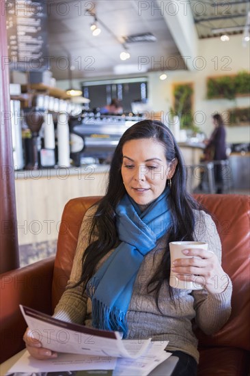 Hispanic woman reading paperwork in cafe