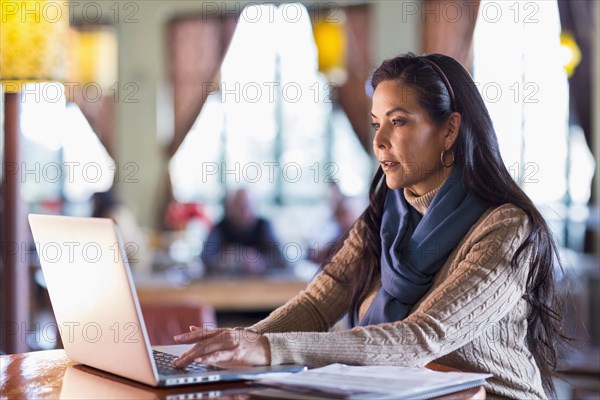 Hispanic woman using laptop in cafe
