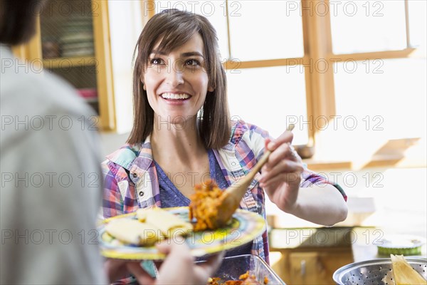 Hispanic woman serving boyfriend in kitchen