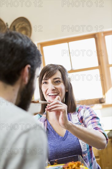 Hispanic woman serving boyfriend in kitchen